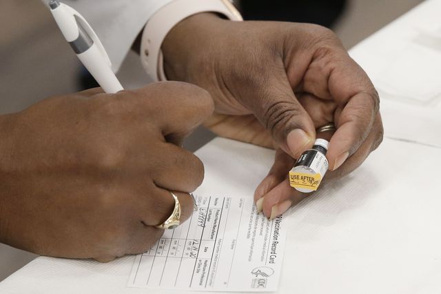 Dr. Michelle Chester fills out a vaccination record card after giving the Pfizer-BioNTech coronavirus vaccine to Dr. Duroseau Yves at Long Island Jewish Medical Center Northwell Health in New York City on Monday, December 14, 2020.